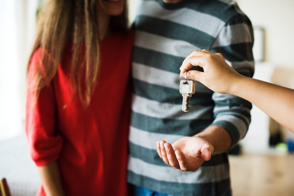 a person handing over keys to a couple