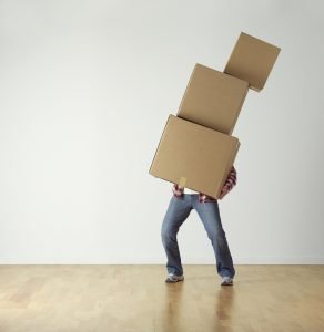 A man carrying three boxes. Lift the boxes properly to avoid injuries while moving.