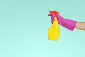 A person holding a detergent in spray for cleaning before packing a nursery for relocation