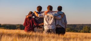 four friends hugging in a field