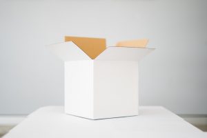 An open white box on a white table in a white room