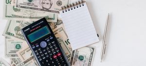 a calculator and a notebook on a stack of money