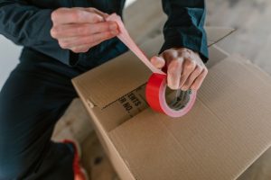 a man taping the box - plan your cross-country moving costs