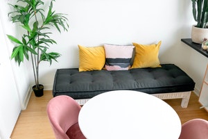 A white table and pink chairs next to a sofa
