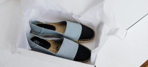 An open box with a pair of black and blue shoes;