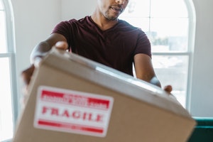 A man holding a box with a fragile sticker on it