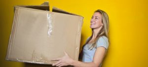 A woman holding a box from the list of items when moving by yourself
