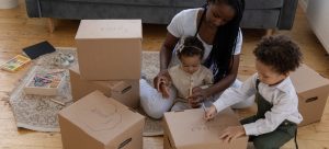 Children and their mother writing on cardboard boxes 