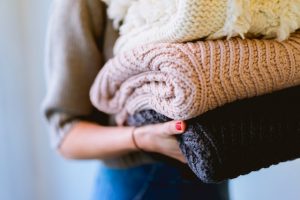 a woman holding sweaters