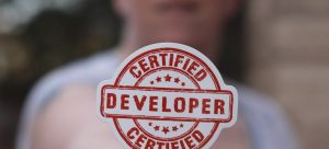A man holding a certified developer badge;