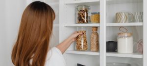 Picture of a woman restocking her pantry and thinking about hidden and forgotten costs of moving