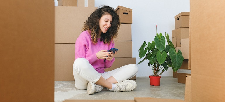 A person surrounded by moving boxes, calling furniture movers Las Vegas